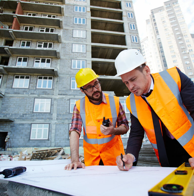 Modern engineer pointing at sketch in blueprint while explaining it to colleague